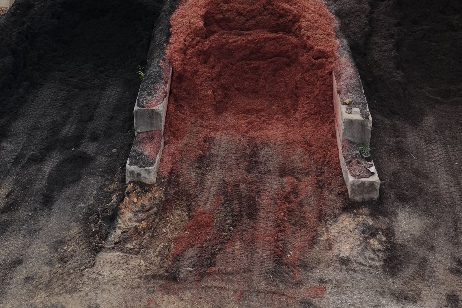 Aerial view of black and red mulch stored in concrete bays at the EWP Mulch yard in Rogers, Arkansas.
